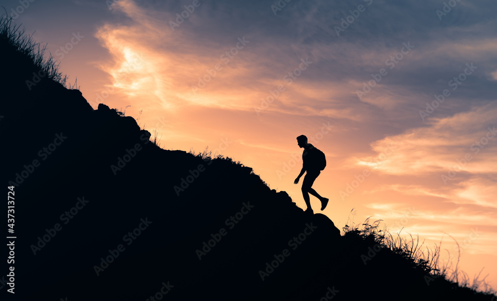 Male hiker climbing up a mountain edge. Adventure, never giving up, life goals concept. 