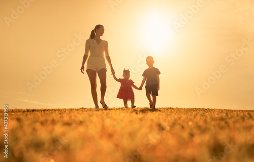 Mother and children walking together outdoors enjoying nature. 