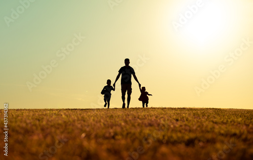 Father and his children walking together holding hands in the park. Fathers Day, family, and parenting concept. 