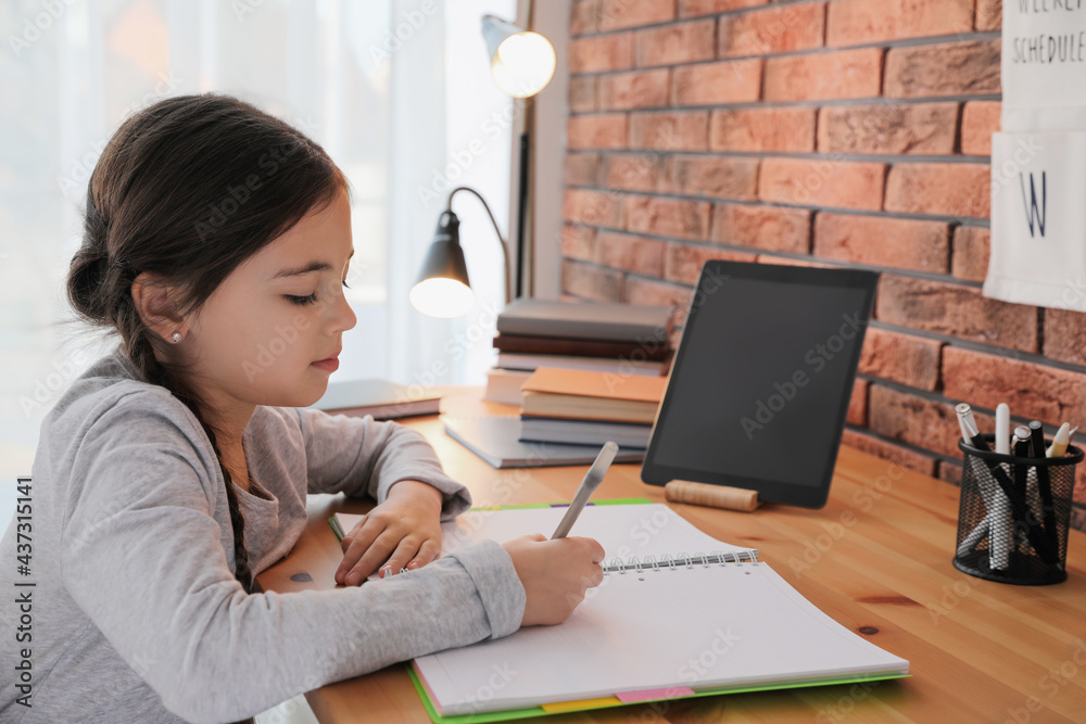 Little girl doing homework with modern tablet at home Little girl doing homework with modern tablet at home