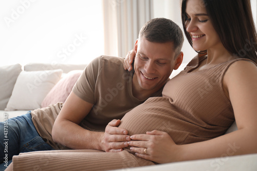 Man touching his pregnant wife's belly at home