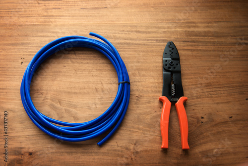 Cable or wire and a wire cutter or crimping pliers on a wooden work desk. photo