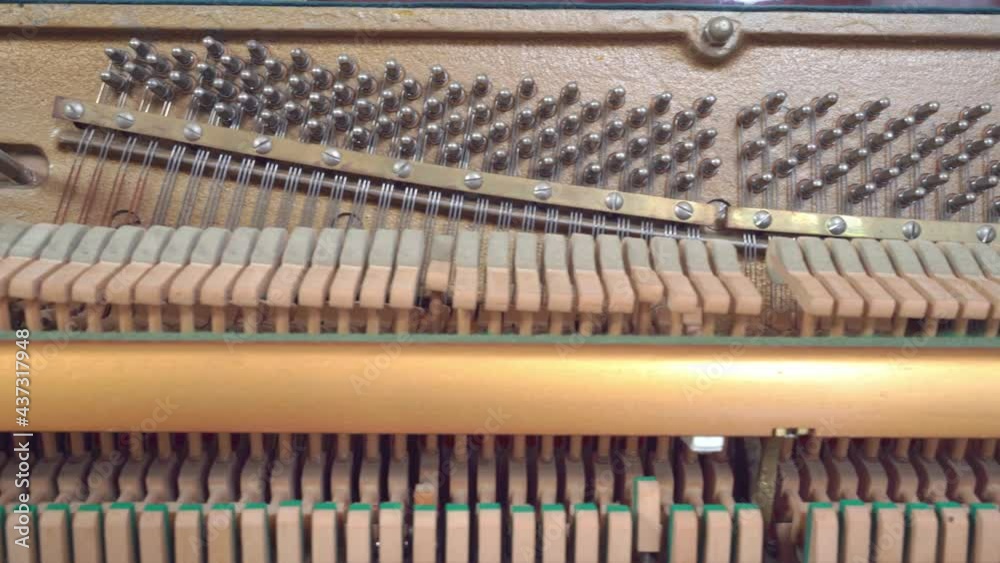 Small wooden hammers tap strings to make sound while musician plays vintage piano at lesson in brightly lit room close view Small wooden hammers tap strings to make sound while musician plays vintage piano at lesson in brightly lit room close view