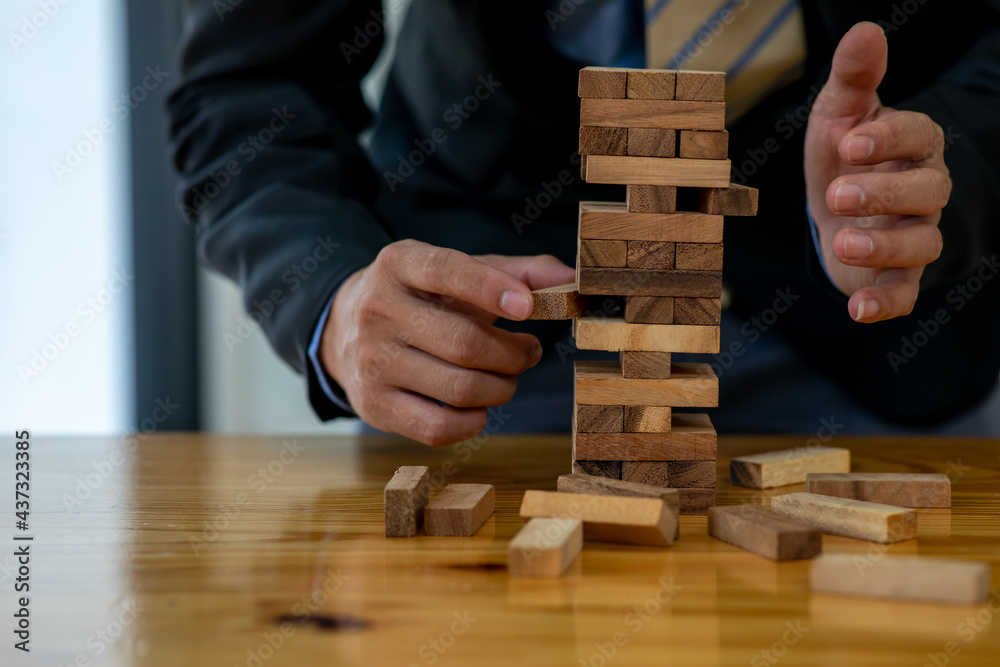 Abstract businessman fail danger tower block game building construction protect plan and project control.	