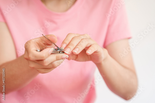 A woman trimmed her fingernails with a nail clipper. The concept of health care of the fingernail.