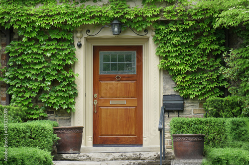 House with elegant wood grain front door surrounded by ivy