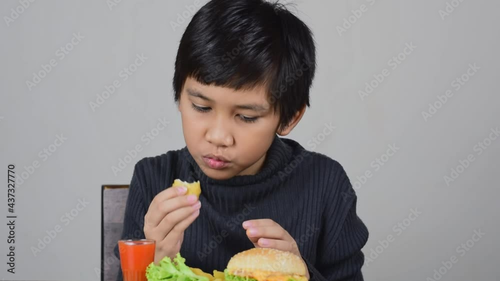 Cute Asian boy eating a delicious chicken nuggets with happiness Cute Asian boy eating a delicious chicken nuggets with happiness