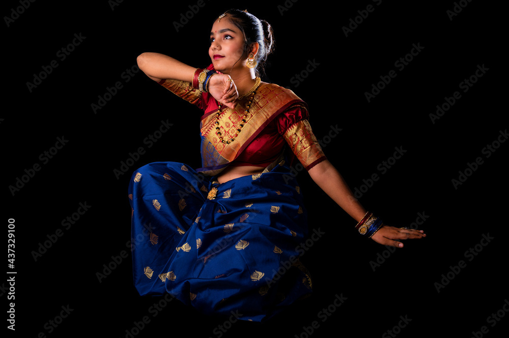 Fototapeta premium Beautiful Indian girl with clean healthy skin on black background. Wear red and blue Marathi saree.