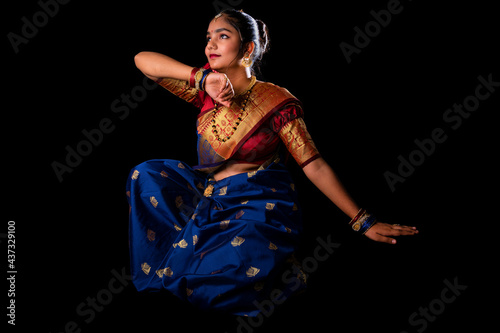 Beautiful Indian girl with clean healthy skin on black background. Wear red and blue Marathi saree.
