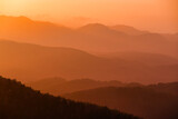 Layered silhouettes of hills and bright orange sunset during sand storm