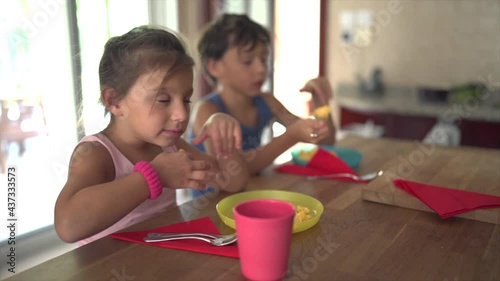 Little girl eating in the kitchen making a funny face that she doesn�t like her food photo