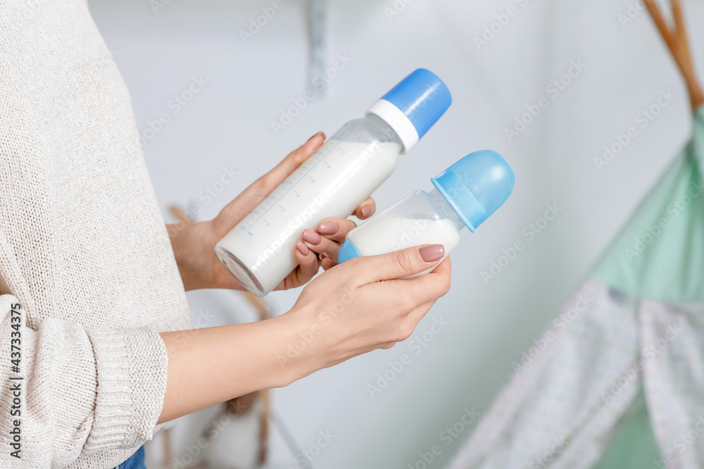 Woman with bottles of milk for baby, closeup Woman with bottles of milk for baby, closeup