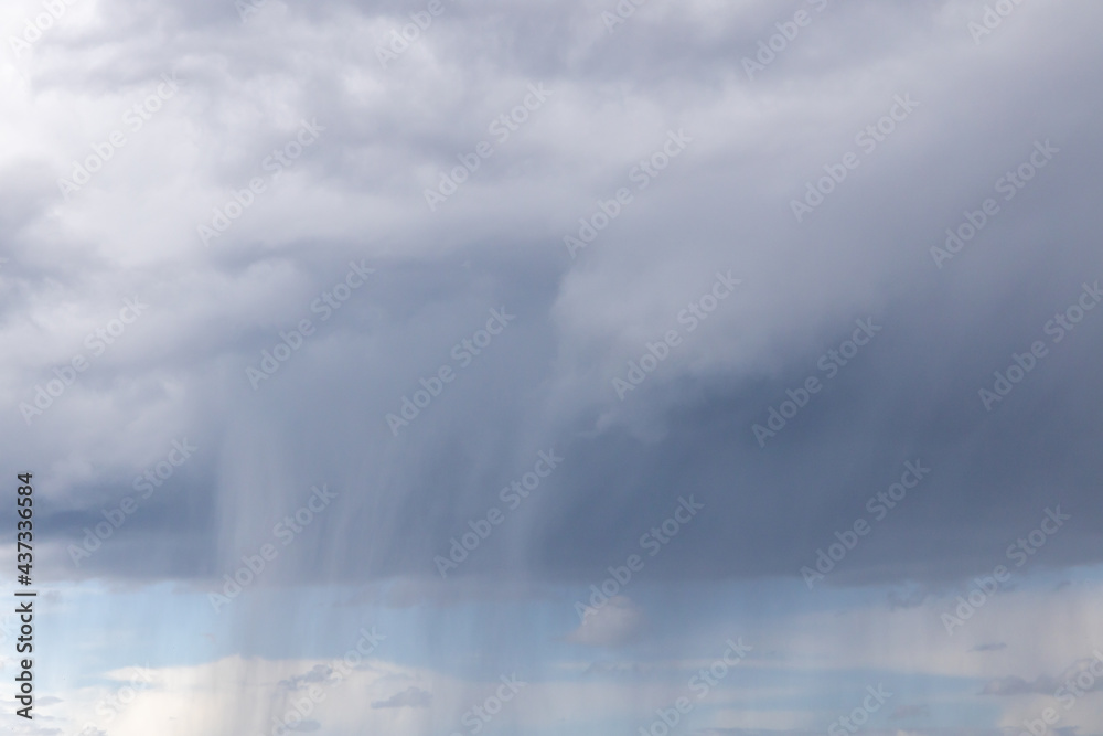 a blue sky with dark storm clouds. Rain clouds are gathering and a thunderstorm is coming. 
