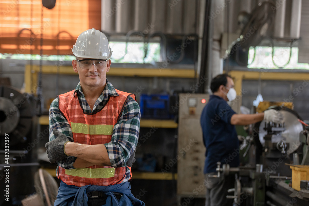 Portrait of a Professional Heavy Industry Engineer Worker Wearing Uniform. factory employee engaged in the production of pin bushing on the lathe in the factory Portrait of a Professional Heavy Industry Engineer Worker Wearing Uniform. factory employee engaged in the production of pin bushing on the lathe in the factory