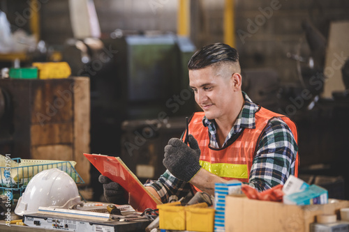 man Lathe worker in production plant drilling at machine on the factory. Industrial engineer worker holding notebook Inspect workpieces