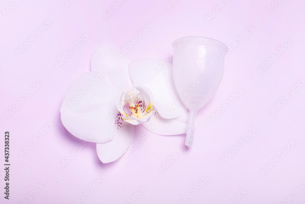 Eco-friendly siliconemenstrual cup with orchid on pink background. Eco-friendly siliconemenstrual cup with orchid on pink background.