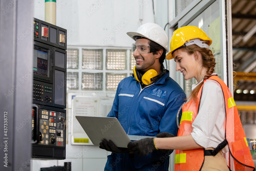 © nikomsolftwaer - portrait of an industrial man and woman engineer with tablet in a factory. Factory worker is programming a CNC milling machine with a tablet computer