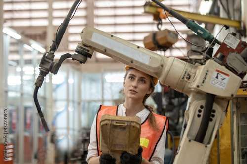Engineer control and check robot working in factory. The worker is controlling the robot to work in the factory. Portrait of female factory worker.  Engineer women are working with machines cnc