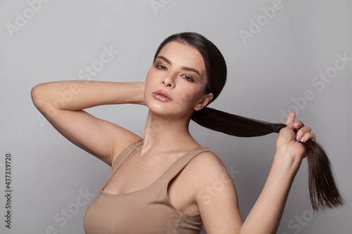 Beautiful young woman touching her ponytail hairstyle with smooth straight hair