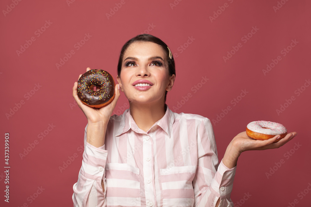 Beautiful woman holding donuts an having fun on pink background. People with sweets