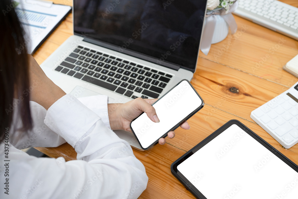Back view of businesswoman holding her mobile phone and sitting at office desk. Back view of businesswoman holding her mobile phone and sitting at office desk.