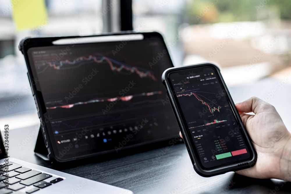 Stock investors hold a phone, open a stock chart viewer to read stock price charts, analyze purchases. Cryptocurrency stocks are popular with both new and old investors. investing in stocks. Stock investors hold a phone, open a stock chart viewer to read stock price charts, analyze purchases. Cryptocurrency stocks are popular with both new and old investors. investing in stocks.