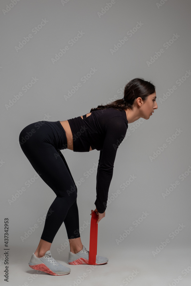 Girl doing deadlifts with resistance loop band in studio Girl doing deadlifts with resistance loop band in studio