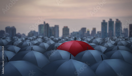unique red umbrella among black umbrellas with city background