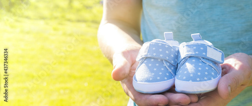 Dad waiting birth of him first son. Man holding small blue baby shoes in hands. Happy parents concept. Pregnant concept.