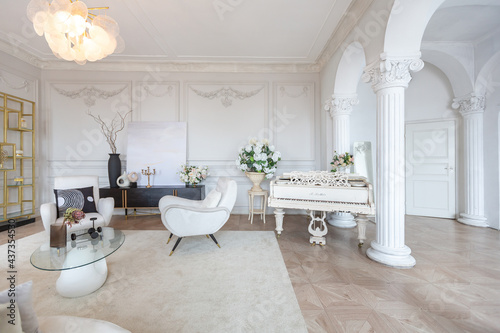 rich luxurious interior of a cozy room with modern stylish furniture nd grand piano  decorated with baroque columns and stucco on the walls