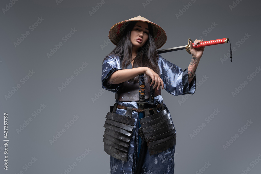 Japanese female killer with katana posing against gray background Japanese female killer with katana posing against gray background