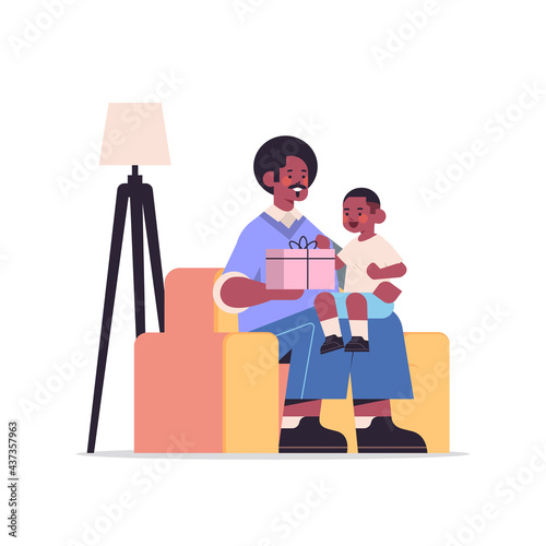 african american father holding gift box for son parenting fatherhood concept dad giving holiday present to his kid
