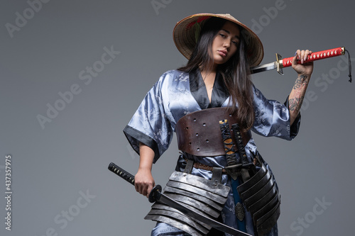 Attractive eastern woman warrior with katana and hat