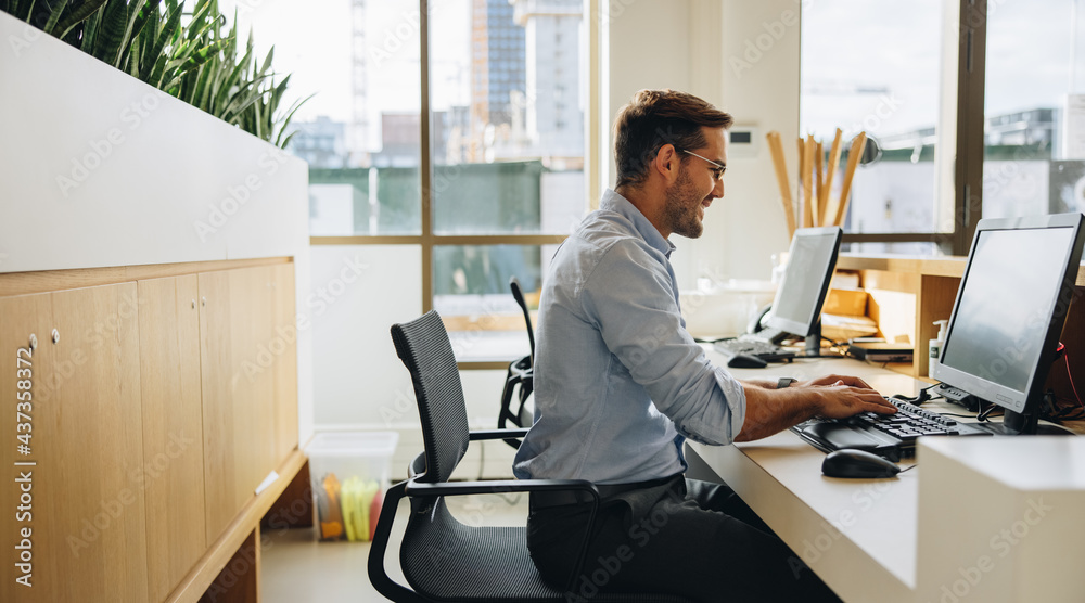 Smiling young man working at his desk Smiling young man working at his desk