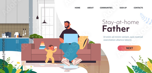 young father playing with little son and using laptop fatherhood parenting concept dad spending time with baby