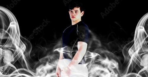 Compostion of caucasian rugby player holding ball on black background with white blur