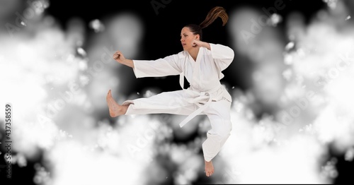 Compostion of caucasian female karate fighter on black background with white blur