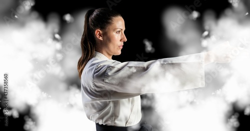 Compostion of caucasian female karate fighter on black background with white blur