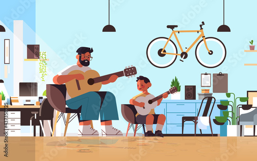 young father teaching little son to play the guitar at home parenting fatherhood concept