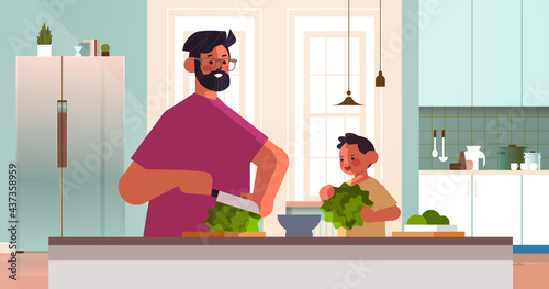 young father and little son preparing healthy vegetables salad at home kitchen parenting fatherhood concept