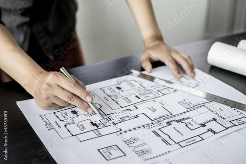 A close-up, an architect, a house designer holding a pen, pointing to a house plan to examine the design plan before discussing the details with the client. Interior design and decoration ideas.