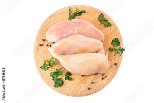 Raw chicken fillet on a round wooden board isolated on white.