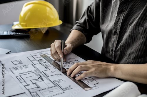 A close-up, an architect, a house designer holding a pen, pointing to a house plan to examine the design plan before discussing the details with the client. Interior design and decoration ideas.