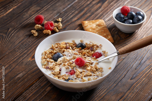 Homemade muesli granola breakfast with plain yogurt, blueberries and raspberries on rustic wooden background. Healthy food clean eating, vegetarian diet, allergy-friendly, weight loosing detox concept