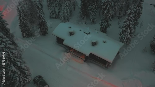 Aerial view of a snowy cabin in the woods of Lapland, winter evening - circling, drone shot photo