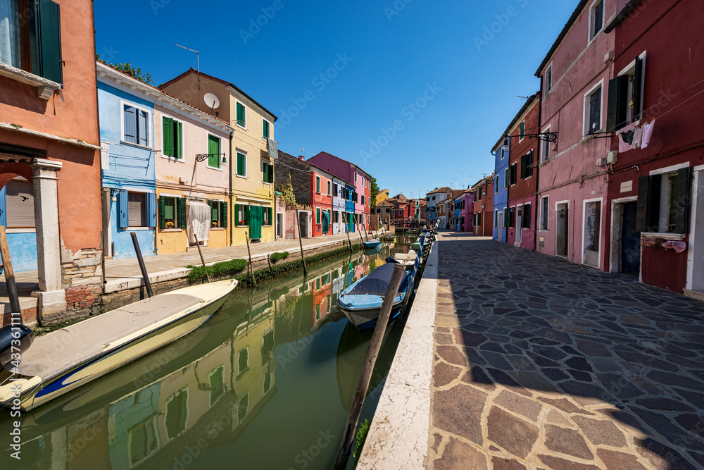 Burano island in a sunny spring day, Venice lagoon, with the multi colored houses and a canal with small boats moored. UNESCO world heritage site, Veneto, Italy, Europe.