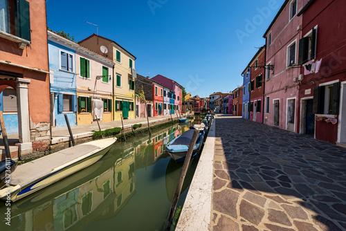 Burano island in a sunny spring day, Venice lagoon, with the multi colored houses and a canal with small boats moored. UNESCO world heritage site, Veneto, Italy, Europe. © Alberto Masnovo