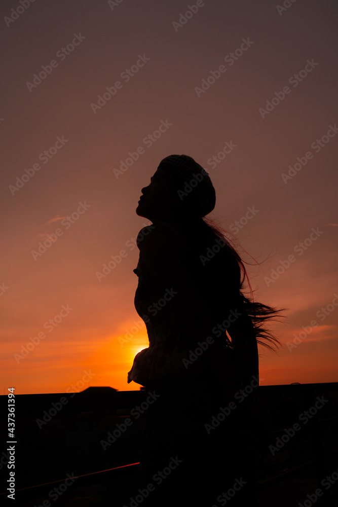 Photo of silhouette adult woman in profile on twilight background. Lonely woman standing alone moments sunset Photo of silhouette adult woman in profile on twilight background. Lonely woman standing alone moments sunset