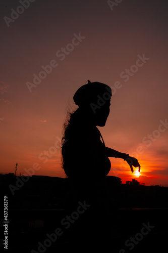Photo of silhouette adult woman in profile on twilight background. Lonely woman standing alone moments sunset