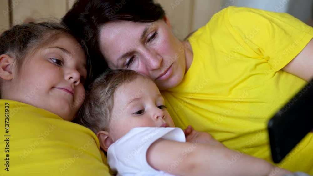 Happy family. Mom, kid and girl watching video on smartphone. Mom, kid and girl communicate over network. Happy family concept. Family watch video on smartphone. Chatting with family over network Happy family. Mom, kid and girl watching video on smartphone. Mom, kid and girl communicate over network. Happy family concept. Family watch video on smartphone. Chatting with family over network